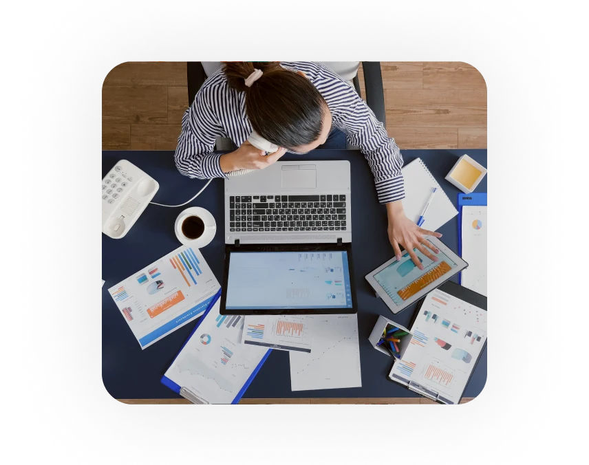 a person sitting at a desk with a laptop and a phone